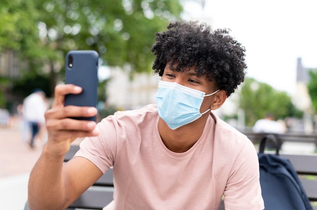 Young man wearing mask outdoors medium shot