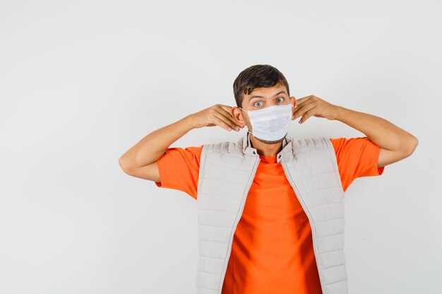 Young man wearing medical mask in t-shirt, jacket