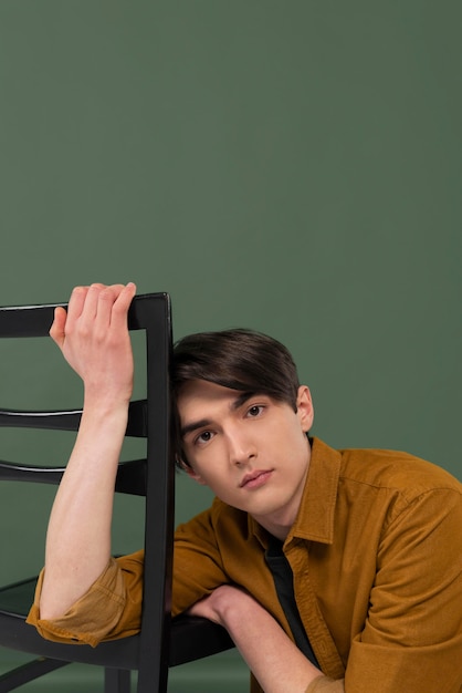 Free photo young man wearing shirt posing on chair