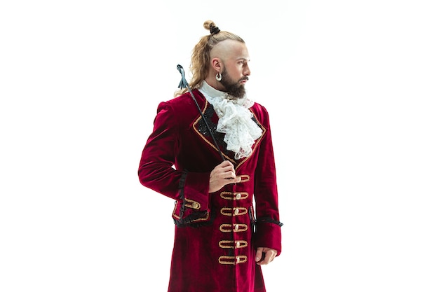 The young man wearing a traditional medieval costume of marquis posing at studio with whip. Fantasy, Antique, Renaissance concept