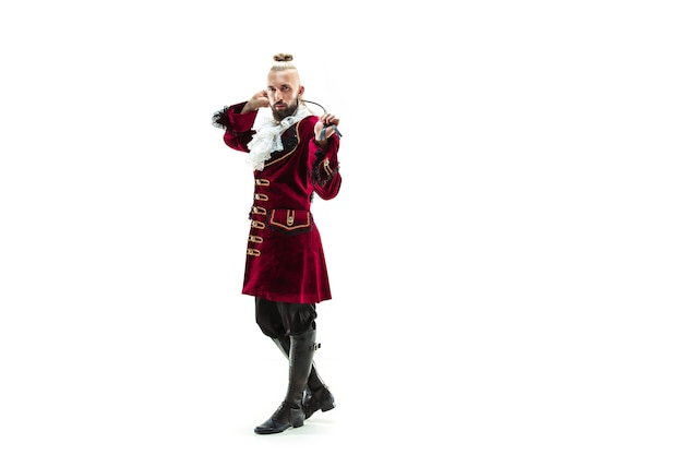 The young man wearing a traditional medieval costume of marquis posing at studio with whip.