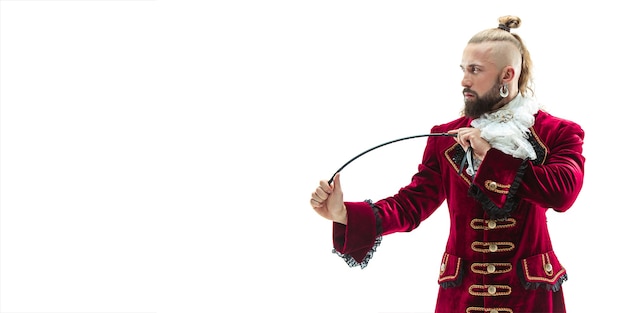 The young man wearing a traditional medieval costume of marquis posing at studio with whip