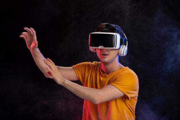 Young man wearing virtual reality headset on the dark surface