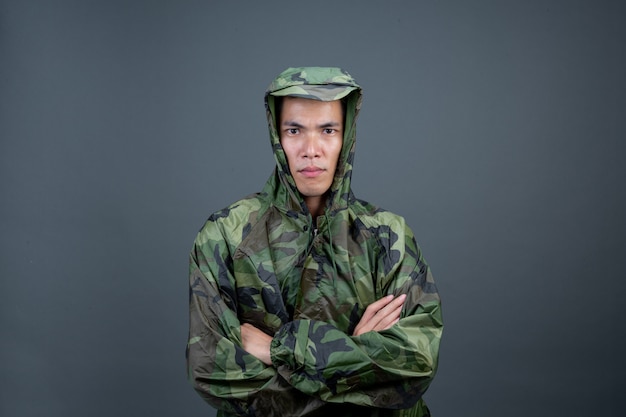 The young man wears a camouflage raincoat and shows different gestures. 