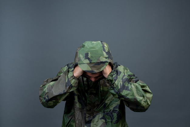 The young man wears a camouflage raincoat and shows different gestures. 