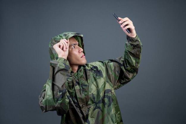 The young man wears a camouflage raincoat and shows different gestures. 