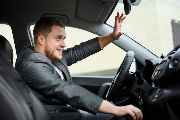 Young man at the wheel greeting someone