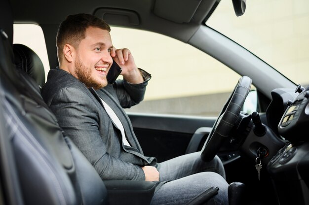 Молодой человек за рулем с телефоном на ухе