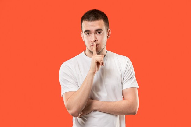 The young man whispering a secret behind her hand over orange background