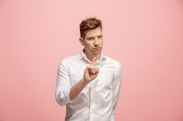 The young man whispering a secret behind her hand over pink background