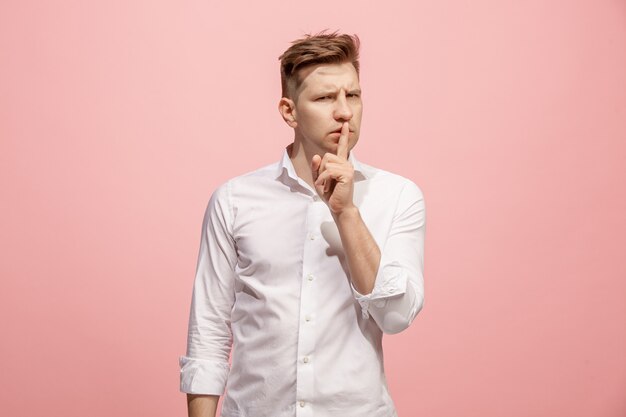 The young man whispering a secret behind her hand over pink background