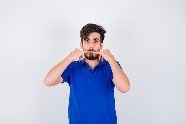 Young man whistling in blue t-shirt and looking serious