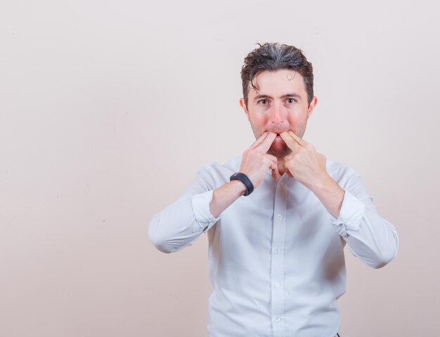 Young man whistling with fingers in white shirt