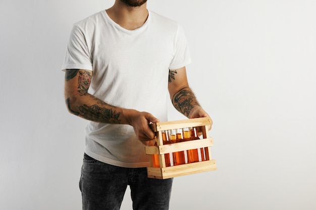 Free photo young man in white cotton t-shirt with tattoos holding a crate of artisan beer isolated on white