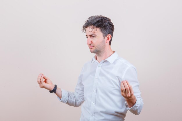 Young man in white shirt doing meditation with closed eyes and looking hopeful