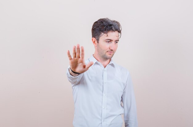 Young man in white shirt showing refusal gesture and looking confident