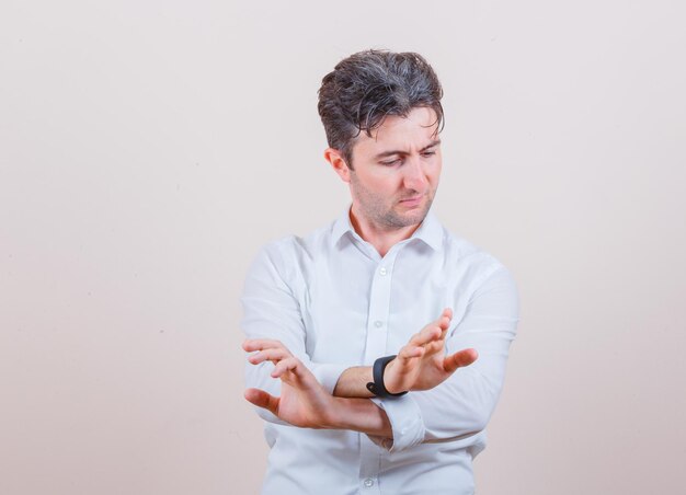 Young man in white shirt showing refusal gesture and looking resolute