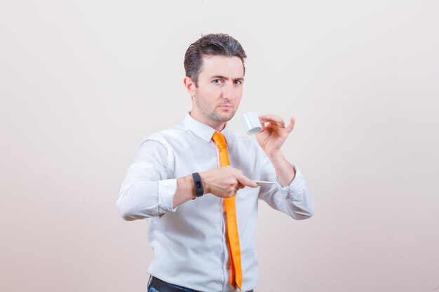 Young man in white shirt, tie drinking turkish coffee and looking pensive