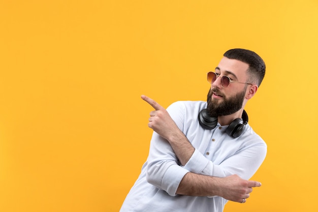 Young man in white shirt with beard, sunglasses and black headphones