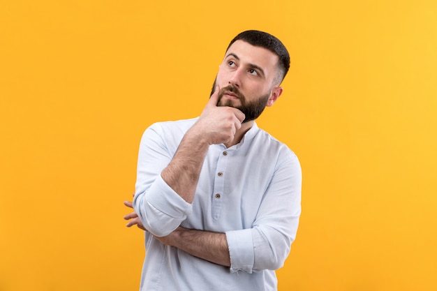 Young man in white shirt with beard thinking expression