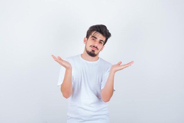 Young man in white t-shirt showing helpless gesture and looking confused