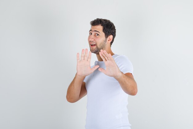 Young man in white t-shirt showing 'thanks but no' gesture