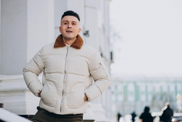 Young man in white winter jacket outside the street