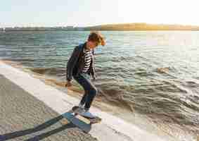 無料写真 海のそばのスケートボードを持つ若い男