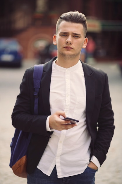 Young man with backpack holding a phone