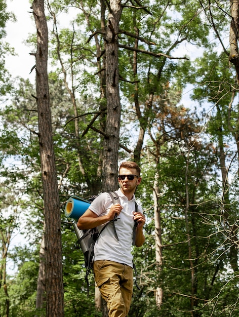 Бесплатное фото Молодой человек с рюкзаком в лесу