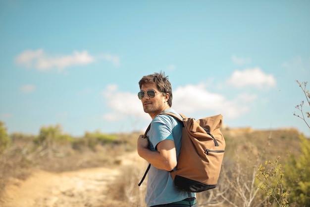 young man with backpack walks in the countryside