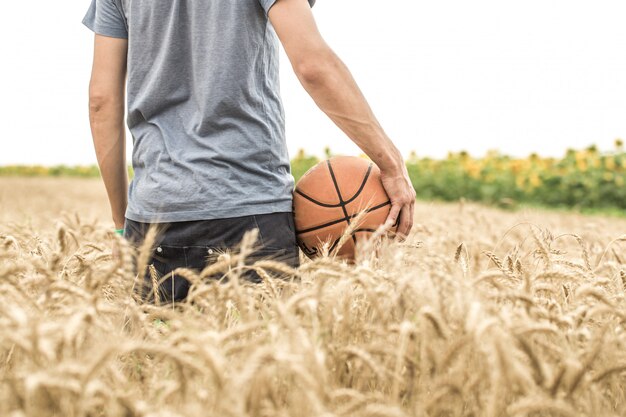 молодой человек с баскетбольным мячом на природе, концепция спорта