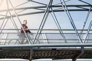 Foto gratuita giovane con la bicicletta sul ponte