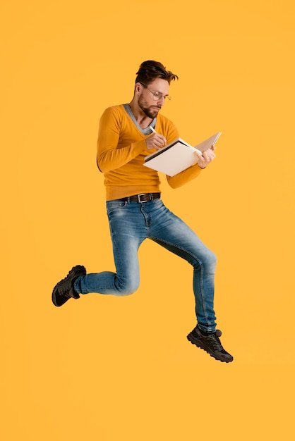 Free photo young man with book jumping