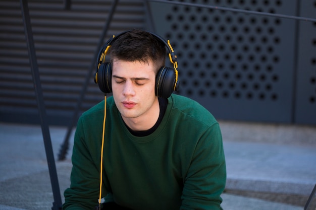 Young man with closed eyes listening to music in headphones