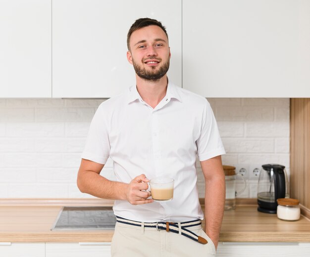 Young man with coffee smiling at camera