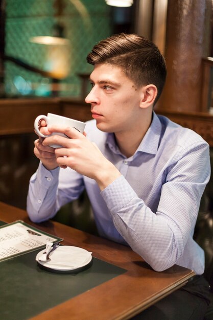 ホット飲み物のカップを持つ若い男