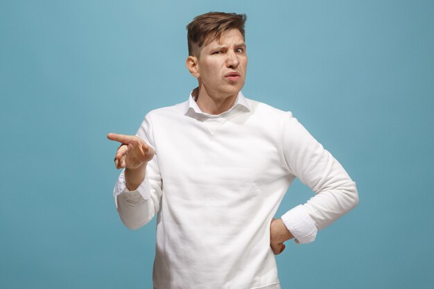 Young man with disgusted expression repulsing something, isolated on the blue