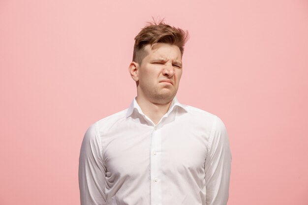 Young man with disgusted expression repulsing something, isolated on the pink