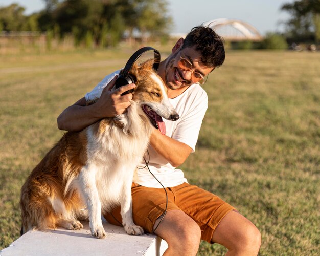 ヘッドフォンで海辺で犬と若い男