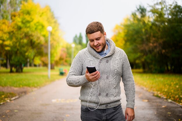 Young man with earphones looking at smartphone