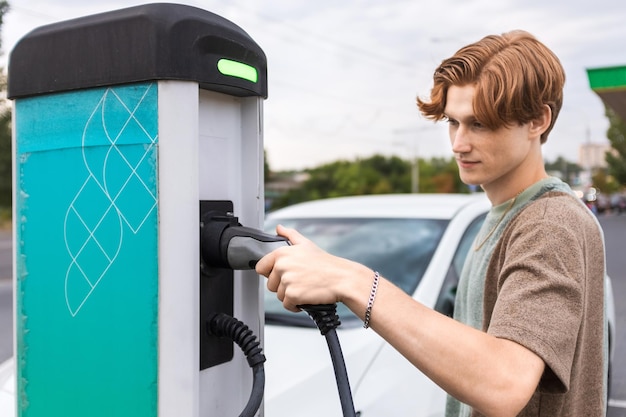 キシナウ モルドバの充電ステーションで電気自動車を持つ若者