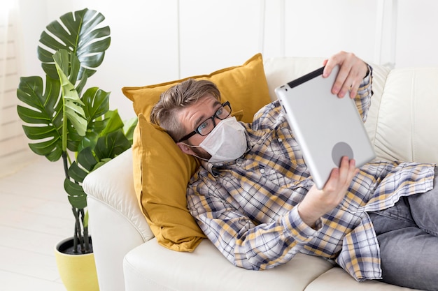 Free photo young man with face mask holding tablet