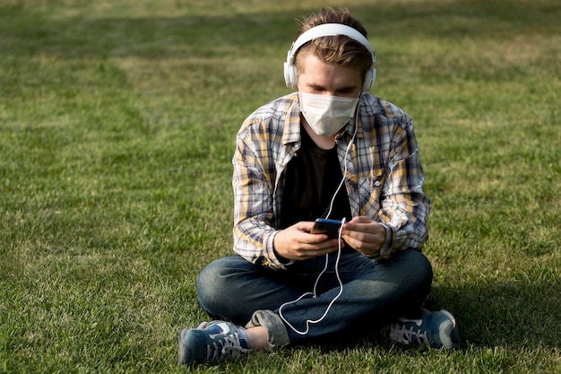 Young man with face mask listening to music