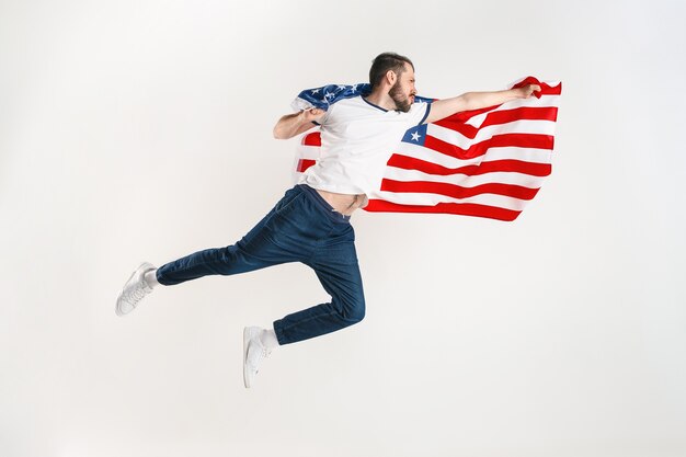 白いスタジオで隔離のアメリカ合衆国の旗を持つ青年。