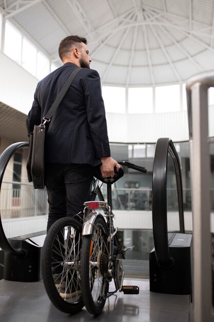 エスカレーターで折りたたみ自転車を持つ若い男