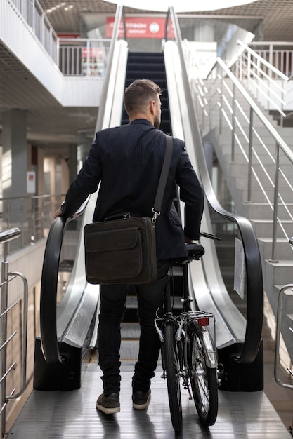 エスカレーターで折りたたみ自転車を持つ若い男