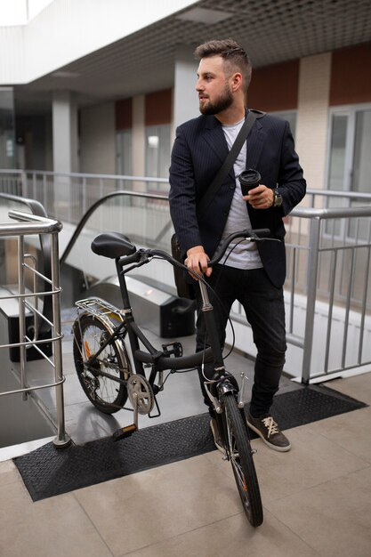 エスカレーターで折りたたみ自転車を持つ若い男