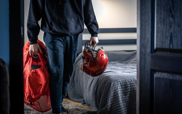 A young man with a football helmet in his room