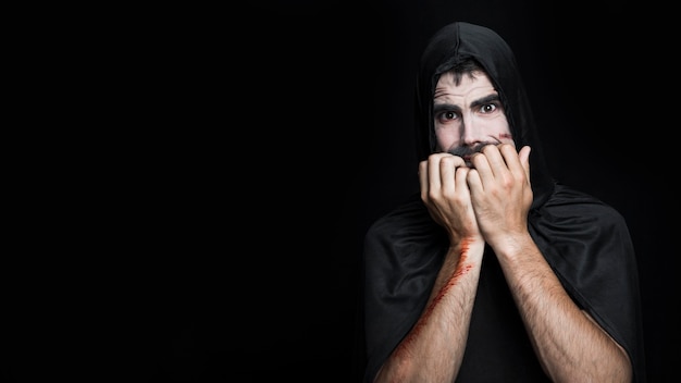 Young man with frightened face in Halloween costume posing in studio